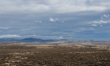 Güzel sonbahar manzarası ufukta dağlar, kuru çimenler, ağaçlar, yollar, bahçeler ve tarlalar, tüylü açık gri bulutlu sıra dışı mavi gökyüzü.
