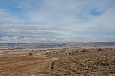 Güzel sonbahar manzarası ufukta dağlar, kuru çimenler, ağaçlar, yollar, bahçeler ve tarlalar, tüylü açık gri bulutlu sıra dışı mavi gökyüzü.