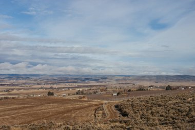 Güzel sonbahar manzarası ufukta dağlar, kuru çimenler, ağaçlar, yollar, bahçeler ve tarlalar, tüylü açık gri bulutlu sıra dışı mavi gökyüzü.