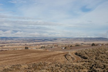 Güzel sonbahar manzarası ufukta dağlar, kuru çimenler, ağaçlar, yollar, bahçeler ve tarlalar, tüylü açık gri bulutlu sıra dışı mavi gökyüzü.