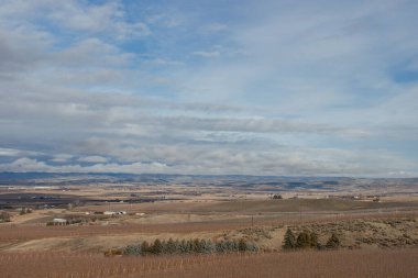 Dağlarla, kuru otlarla, ağaçlarla ve tarlalarla dolu güzel sonbahar manzarası. Koyu gri bulutlu sıra dışı büyük gökyüzü.