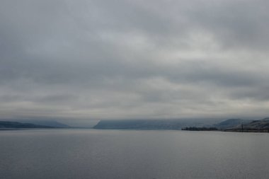 Mavi-gri ölçekte güzel sisli bir manzara: ufukta koyu mavi dağlar, kuru çimlerle kaplı tepelerin kıyısında geniş bir nehir vardır. Colorado Nehri, OR, ABD