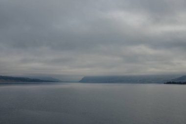 Mavi-gri ölçekte güzel sisli bir manzara: ufukta koyu mavi dağlar, kuru çimlerle kaplı tepelerin kıyısında geniş bir nehir vardır. Colorado Nehri, OR, ABD
