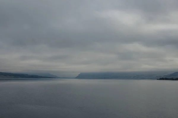 Mavi-gri ölçekte güzel sisli bir manzara: ufukta koyu mavi dağlar, kuru çimlerle kaplı tepelerin kıyısında geniş bir nehir vardır. Colorado Nehri, OR, ABD