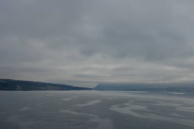 Mavi-gri ölçekte güzel sisli bir manzara: ufukta koyu mavi dağlar, kuru çimlerle kaplı tepelerin kıyısında geniş bir nehir vardır. Colorado Nehri, OR, ABD