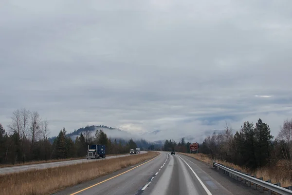 道路两旁都有路标 在高山间的云彩中 卡车和汽车在路上行驶 美国爱达荷州 2020年5月12日 — 图库照片