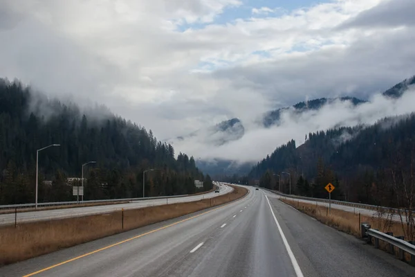 Karayolu Kışın Bulutların Arasında Yüksek Dağların Arasında Yol Işaretleri Olan — Stok fotoğraf