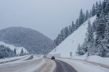 Dağların arasında karla kaplı otoyol, karların arasında ağaçlar ve ağaçlar var. Karla kaplı yolu, Montana, Amerika 'daki köknar ağaçları ve dağları olan kış manzarası, 1-18-2020