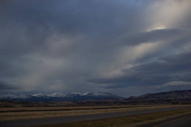 Sonbahar manzarası alacakaranlıkta. Bozkırların arasında asfalt yol, sarı kuru çimenler ufukta mavi dağlar, güzel mavi-gri sonbahar gökyüzü.