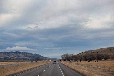 Sonbahar manzarası alacakaranlıkta. Bozkırların arasında asfalt yol, sarı kuru çimenler ufukta mavi dağlar, güzel mavi-gri sonbahar gökyüzü.