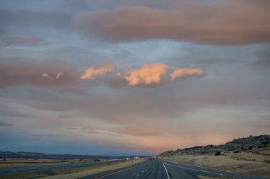 Gün batımında güzel gökyüzü. Otoyol üzerinde koyu mavi ve parlak turuncu bulutlar.