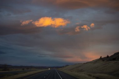 Gün batımında güzel gökyüzü. Otoyol üzerinde koyu mavi ve parlak turuncu bulutlar.