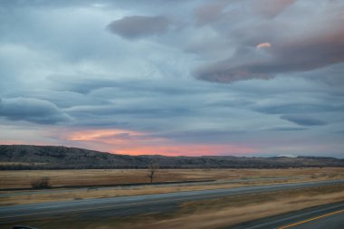 Sonbahar manzarası alacakaranlıkta. Bozkırların arasında asfalt yol, sarı kuru çimenler ufukta mavi dağlar, güzel mavi-gri sonbahar gökyüzü.