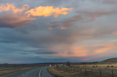 Gün batımında güzel gökyüzü. Otoyol üzerinde koyu mavi ve parlak turuncu bulutlar.
