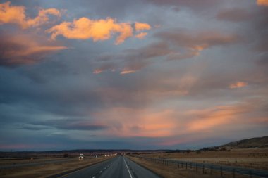 Gün batımında güzel gökyüzü. Otoyol üzerinde koyu mavi ve parlak turuncu bulutlar.