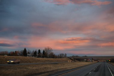 Gün batımında güzel gökyüzü. Otoyol üzerinde koyu mavi ve parlak turuncu bulutlar.
