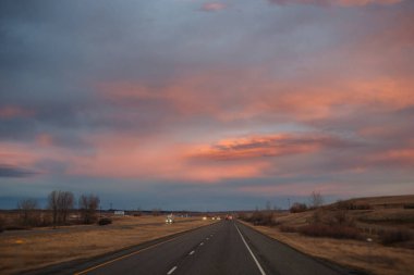 Gün batımında güzel gökyüzü. Otoyol üzerinde koyu mavi ve parlak turuncu bulutlar.