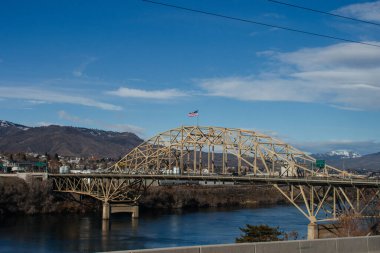 Washington eyaletindeki küçük bir Amerikan kasabasında nehrin üzerinde büyük metal bir köprü. Parlak mavi gökyüzü ile sonbahar güneşli bir gün. 02-08-2020, Washington, ABD
