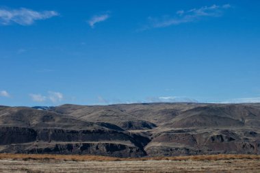 Güzel sonbahar manzarası ufukta dağlar, mavi gökyüzü bulutlar ve yerde kuru çimenler..