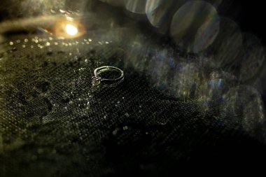 Beyaz altın alyanslar ve koyu arkaplanlı bir elmas. Güzel röfleler ve bokeh. Düğün geçmişi