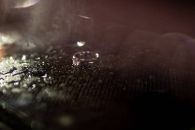 Beyaz altın alyanslar ve koyu arkaplanlı bir elmas. Güzel röfleler ve bokeh. Düğün geçmişi