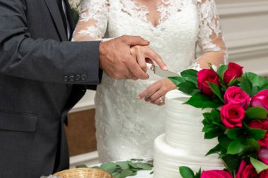 Gelin ve damat el ele tutuşup fuşya gülleriyle süslenmiş bir düğün pastası kestiler.