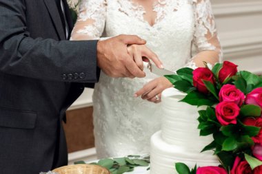 Gelin ve damat el ele tutuşup fuşya gülleriyle süslenmiş bir düğün pastası kestiler.