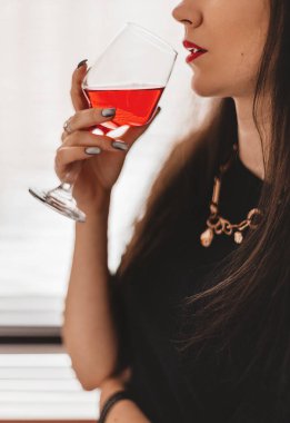 Güzel bir kızın ellerinde bir kadeh kırmızı şarap.