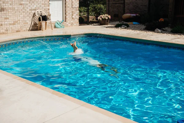 Young handsome man swims in a pool of blue water on a sunny summer day. Summer background