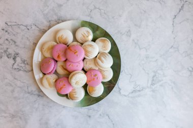 Pembe ve beyaz makaronlar bir tabakta yatıyor. Hafif arka planda tabakta nefis kurabiyeler. Fırın