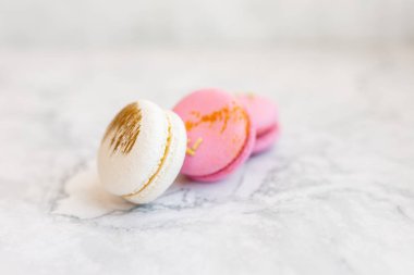 Makarnalar yaklaşsın. Masada pembe ve beyaz badem kurabiyeleri.