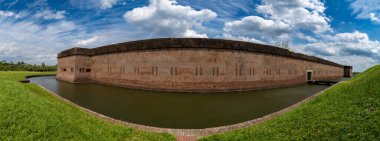 Heybetli bir Üçüncü Sistem duvarcılık kalesi olan Fort Pulaski, dramatik bir gökyüzünün altındaki koruyucu hendeği ile çevrili duruyor. 1829 ve 1847 yılları arasında Gürcistan 'ın Savannah limanını savunmak için Amerikan Ordusu Mühendisler Birliği tarafından inşa edilmiş.