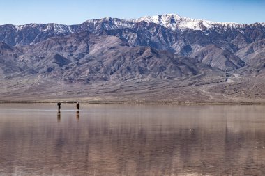 Uçsuz bucaksız bir çöl havzasının inanılmaz derecede durgun ve sığ sularında yüzen iki kişinin yansımaları geniş gökyüzünü yansıtıyor. Bu eşsiz, yansıtıcı manzarayı keşfediyorlar. Uzaktaki dağların görkemli, karlı dağlarıyla.