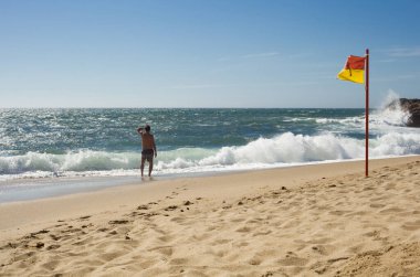 Şehir plajında sarı-kırmızı bayraklı bir adam - yüzmek için güvenli bir yer - Porto - Portekiz