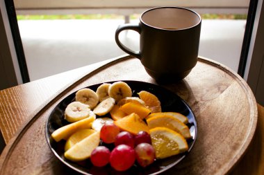 Yakın plan kahvaltı, arka planda taze meyve dilimleri ve bulanık kahve fincanı olan bir hayat. Parlak bir ışık, parlak ışıklar ve samimi, davetkar bir ortam yaratır..
