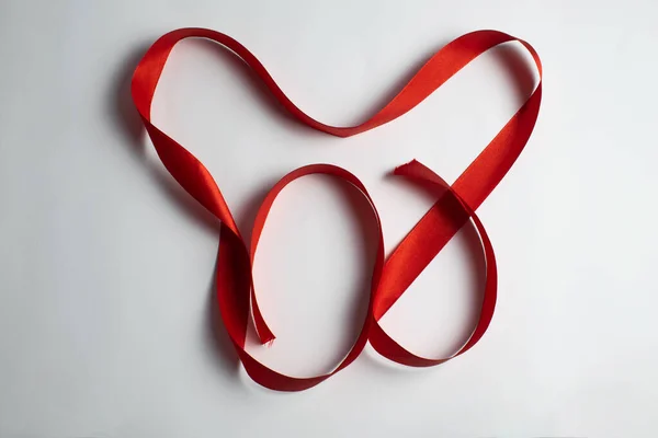 Kırmızı kurdele, kalp şeklinde katlanmış. Sevgililer Günü.