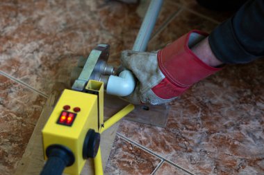 Bir işçi lehimleme demiriyle plastik bir boruyu lehimler..