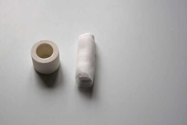 Adhesive plaster and bandage are on a white table. Copy space.