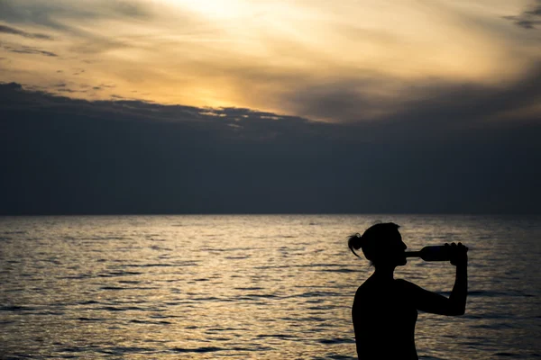 Silueta de niña en la playa al atardecer — Foto de Stock