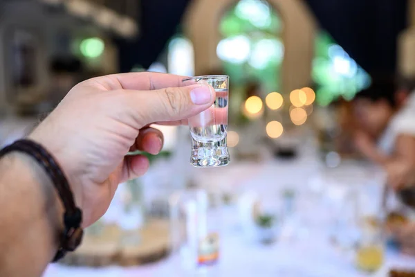 Conceito de casamento ou festa. Mão com um copo de vodka convidado faz um brinde, levantando um copo — Fotografia de Stock