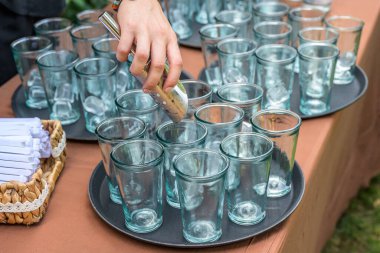 Düğün partisinde barmen elinde kaşıkla bardaklara buz koyuyor.