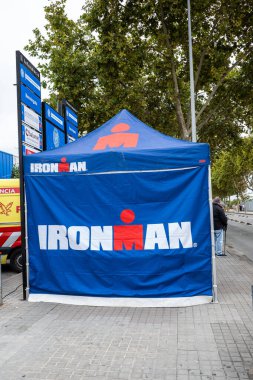 Barselona, İspanya-5 Ekim 2025. Sokakta logolu Ironman olay çadırı, arkada ağaçlar.