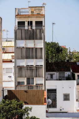 Narrow Residential Tower with Exterior Blinds in City, density, vertical living, apartment life, sun protection, and urban residential architecture.