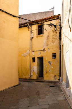 Sarı duvarları ve klasik mimarisi olan eski bir Akdeniz köyü sokağı.