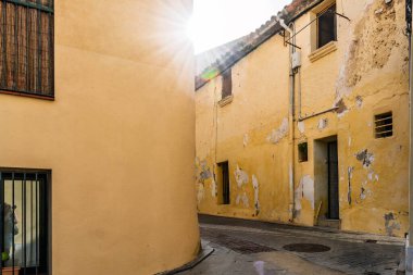 Sarı duvarları ve klasik mimarisi olan eski bir Akdeniz köyü sokağı.