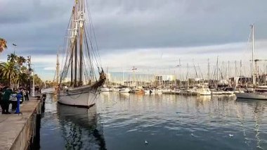 Barselona, İspanya-24 Kasım 2025. Klasik uzun gemi ve lüks yatlarla Barselona marinasının panoramik manzarası.