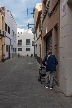 Dar bir şehir sokağında yürüyen bir yaşlı..