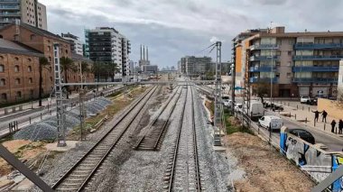 Barcelona yakınlarındaki Sant Adri de Bess 'te üç baca elektrik santrali arka planında demiryolu ve şehir manzarası var..
