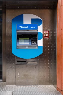 Barselona, İspanya-23 Kasım 2025. Para çekmek için metal bir duvara gömülü bir Banco Sabadell otomatik veznedar makinesinin dış cephesi