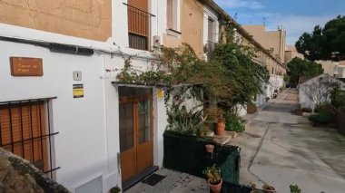 Geleneksel Akdeniz mimarisi ve saksı bitkilerinin yer aldığı Badalona 'nın Dalt de la Vila semtinde sakin ve tarihi bir cadde manzarası.